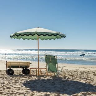 Beach trolley, chair and umbrella at Coolum Beach on a sunny day. You can see the sand and water.